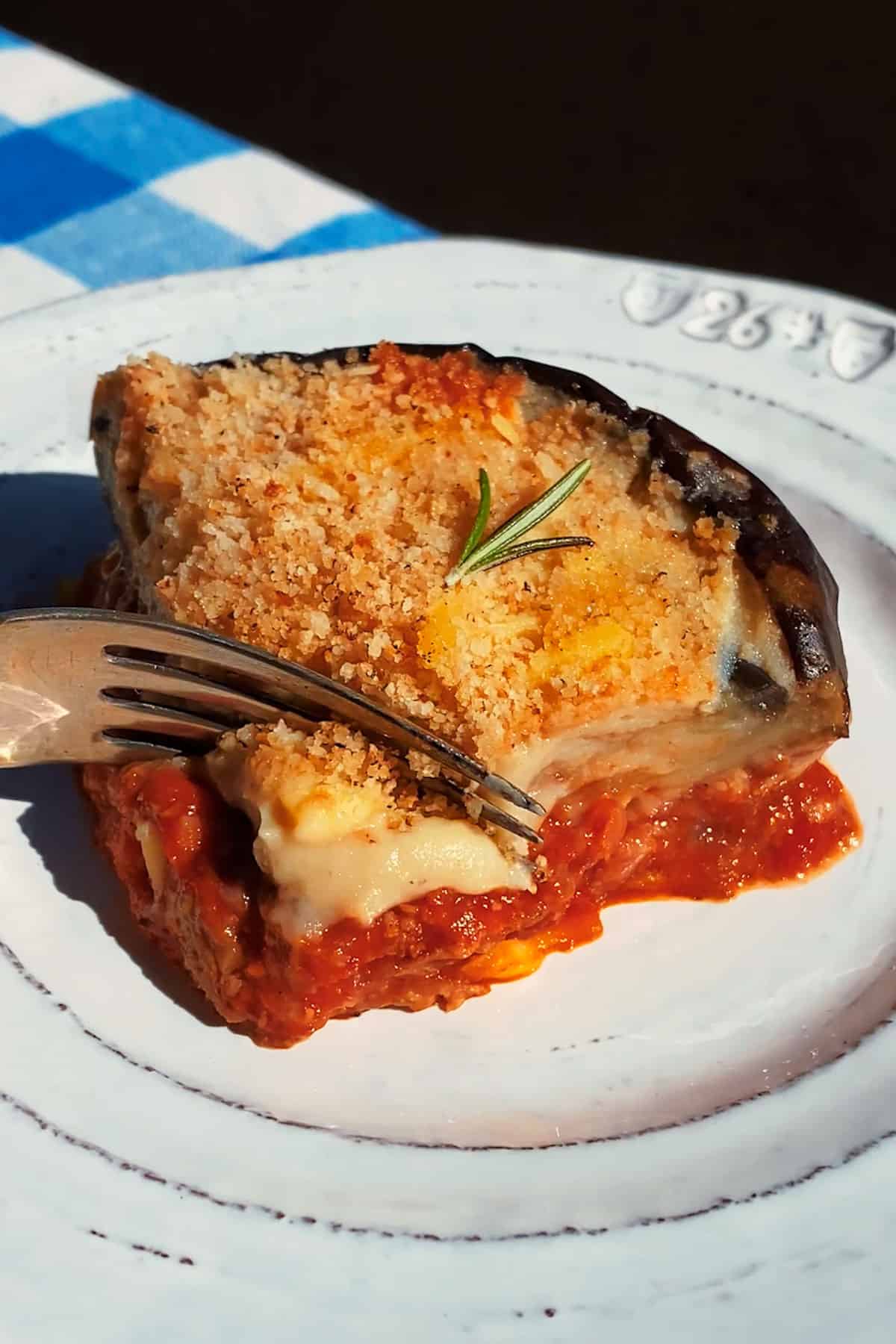 vegan moussaka sliced with a fork in direct sunlight