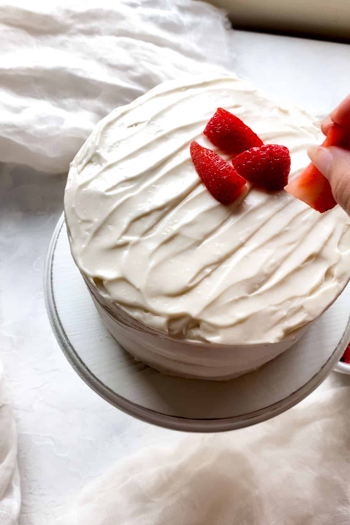 placing strawberries onto a frosted cake