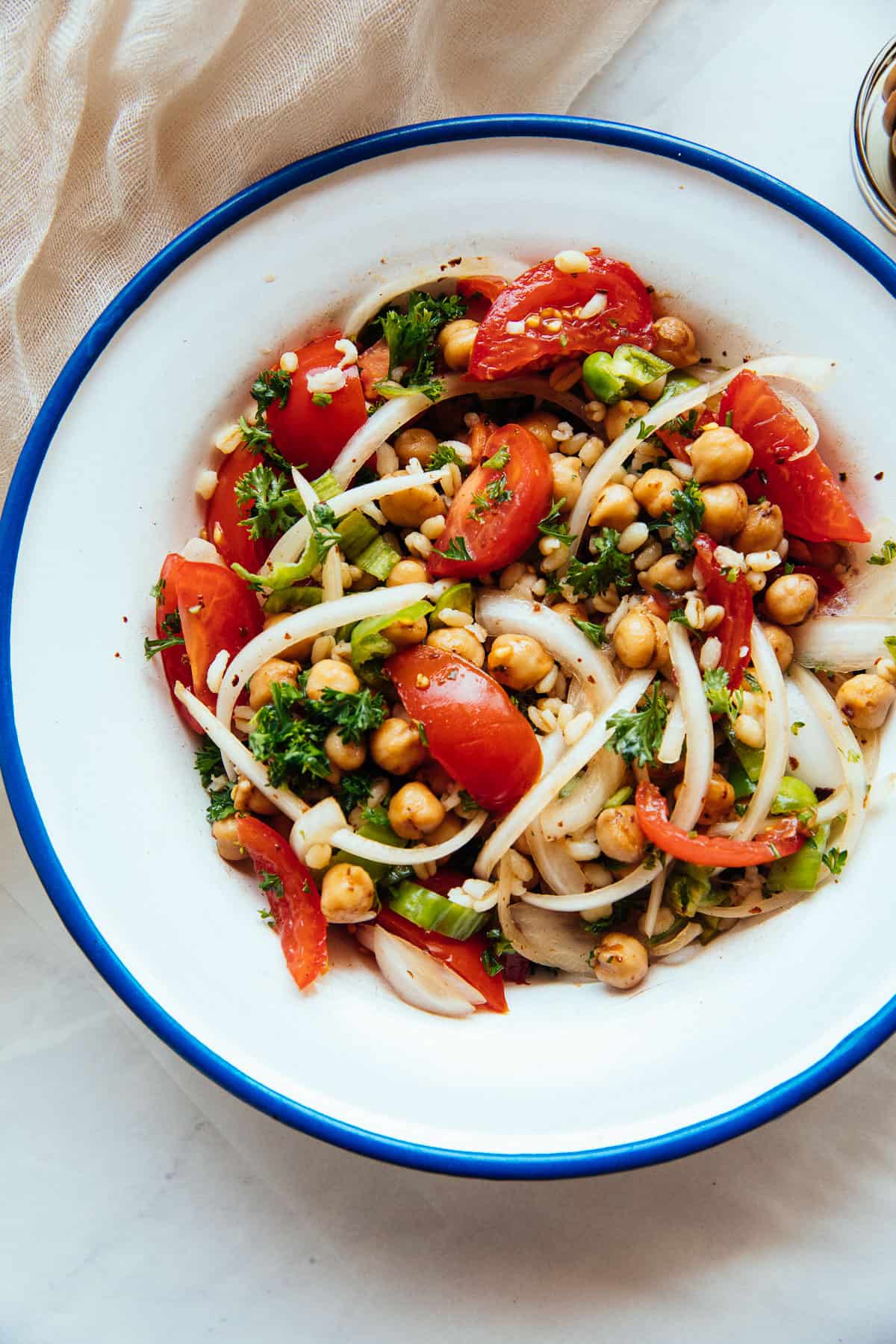 Mediterranean chickpea salad in a bowl with onions, sumac, and tomatoes