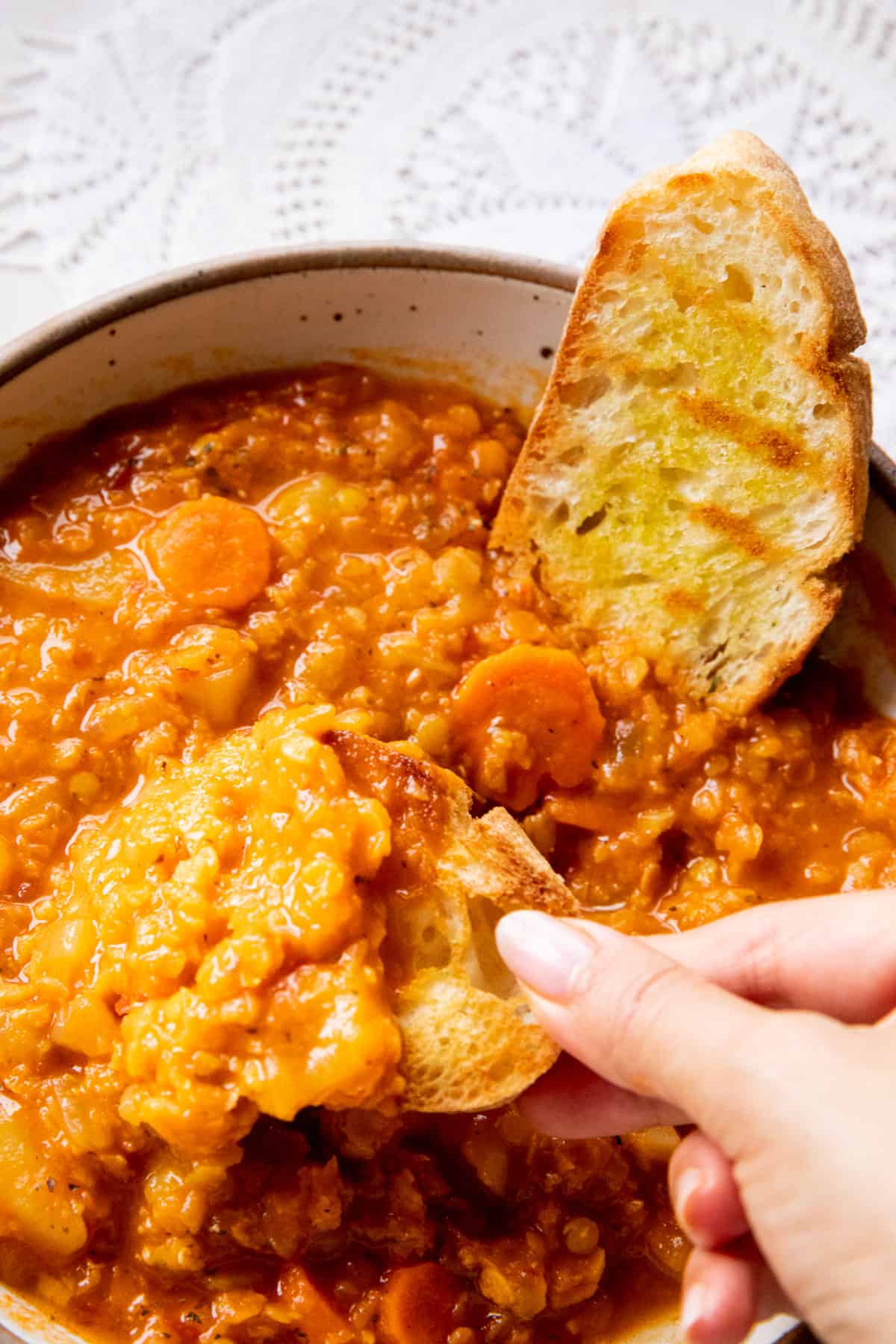 lentil soup being scooped up by woman's hand