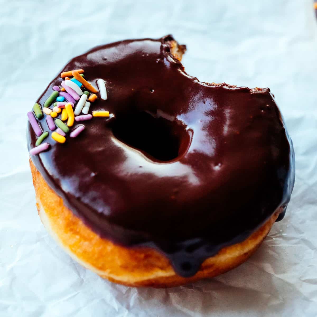 vegan chocolate glaze donuts with sprinkles bit into