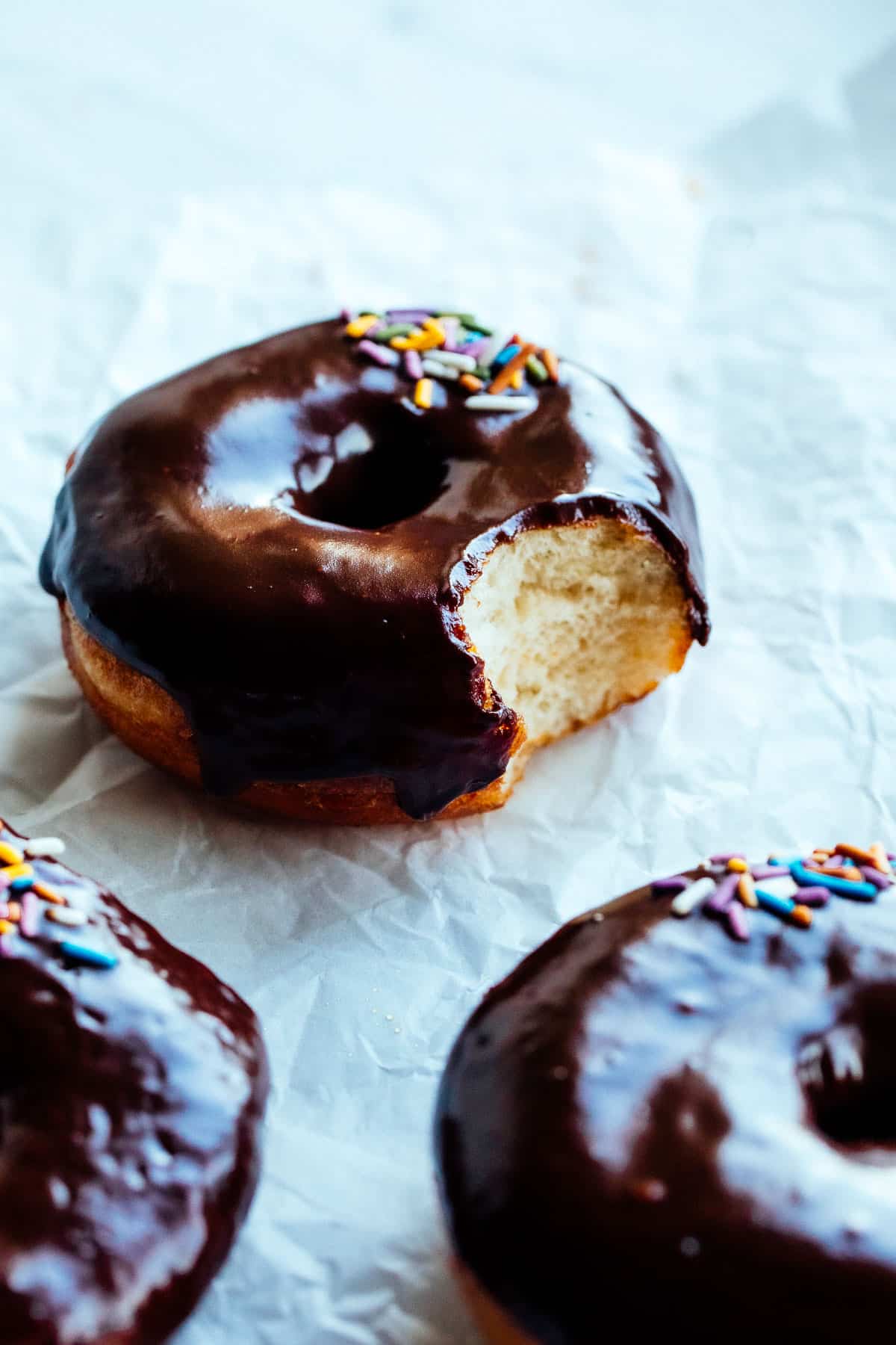 vegan chocolate glaze doughnuts with sprinkles bit into from the side