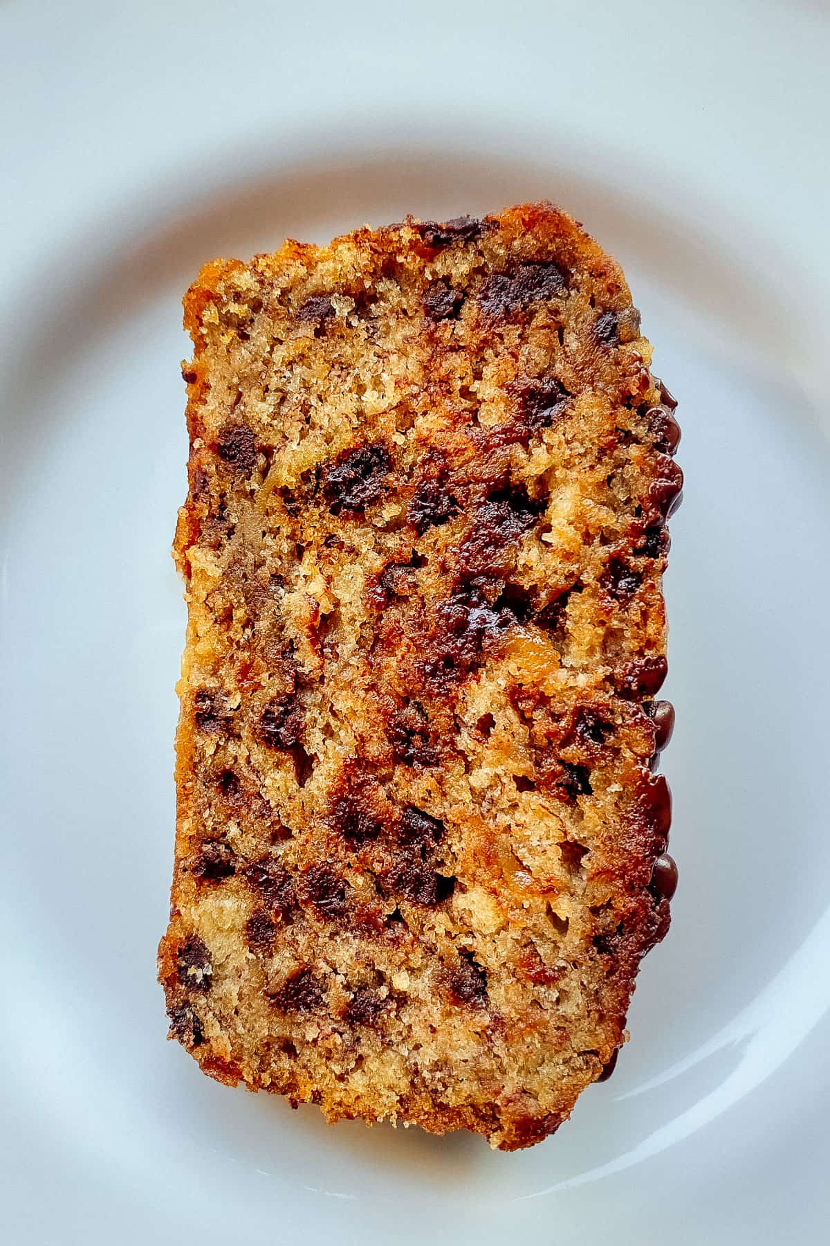 A slice of chocolate chip banana bread on a white plate